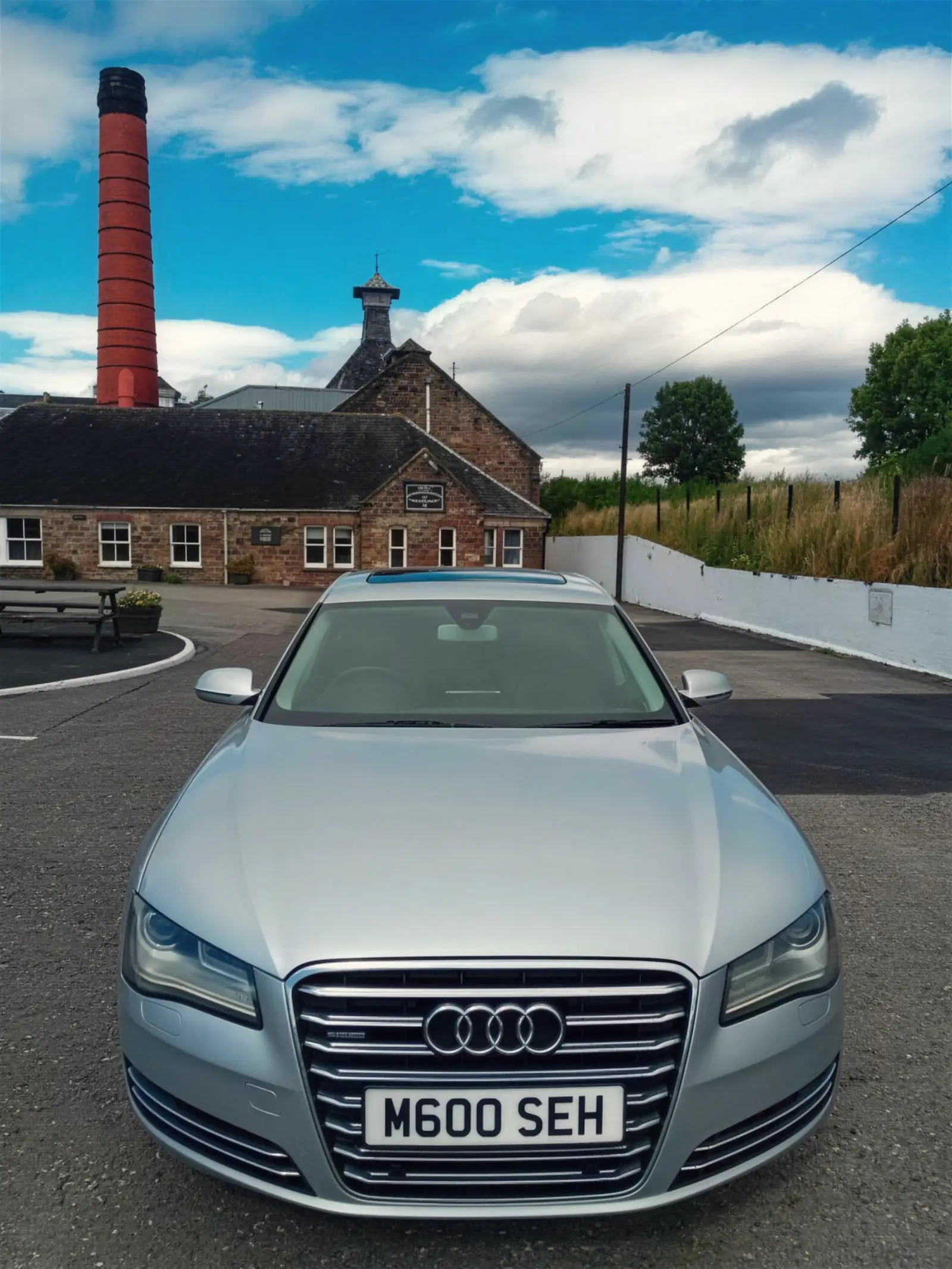 Audi A8 L at a distillery with a red brick chimney