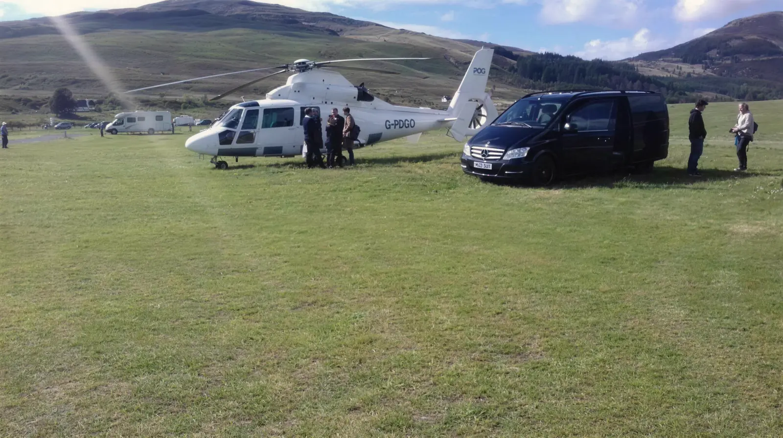 Mercedes-Benz Vito waiting beside a private helicopter on a Highland field