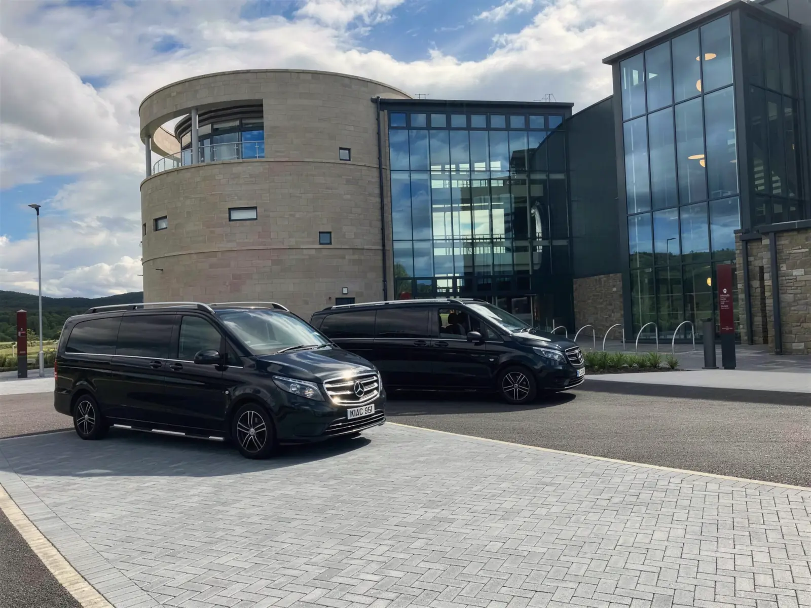 Two Mercedes-Benz Vitos at a modern stone and glass building