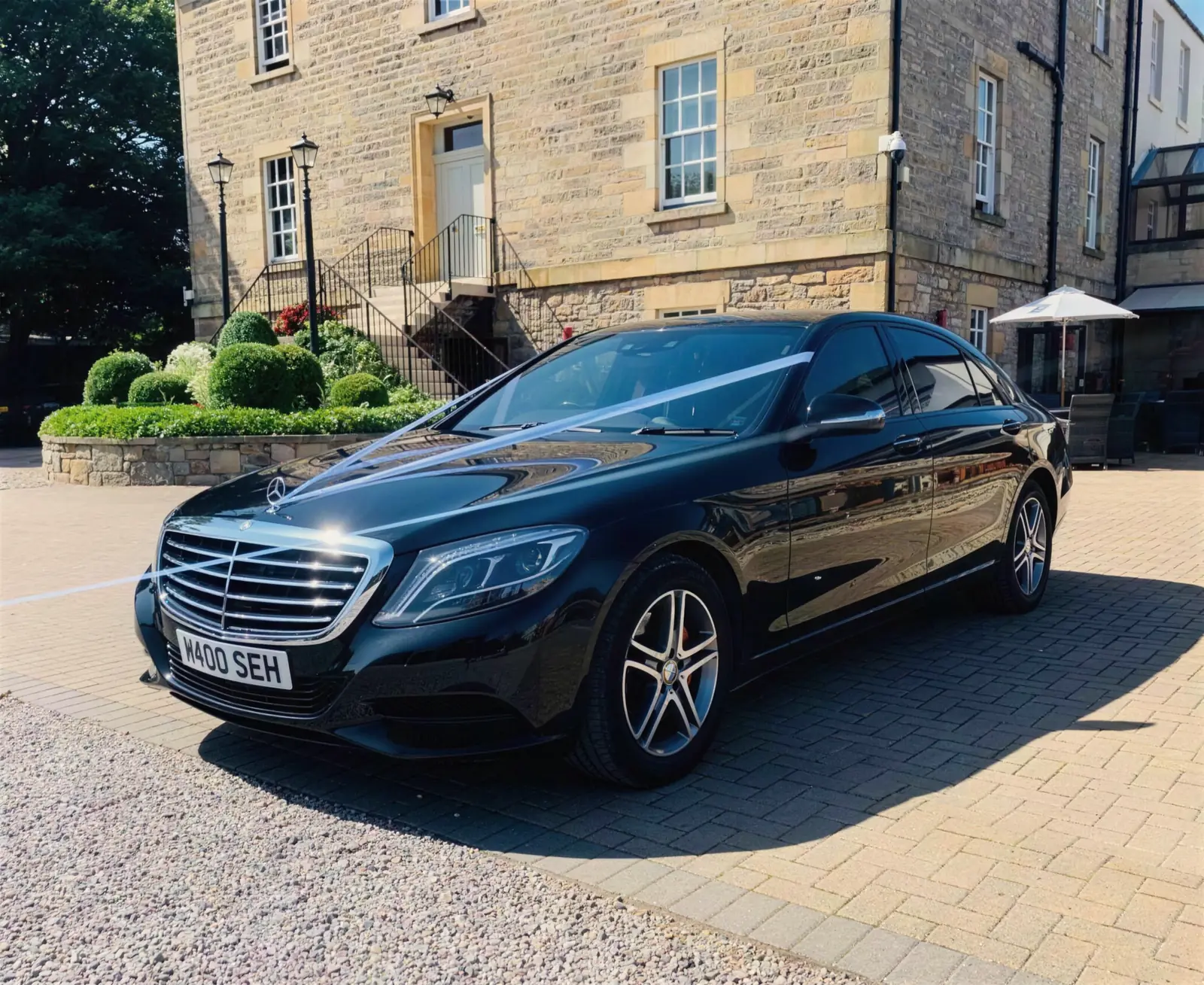 Mercedes S-Class with wedding ribbons outside a hotel